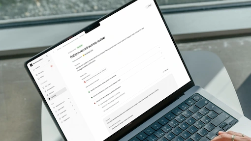 Hybridity patient-record access review on a MacBook Pro used beside an office window.